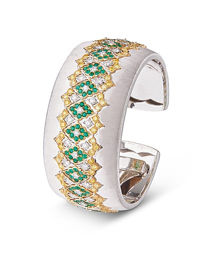 Silver ring with intricate gold lattice design and embedded green gemstones.