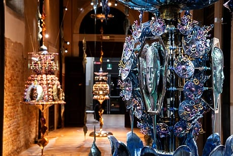 Colorful sculptural art installations displayed in a dimly lit gallery with textured walls and a high ceiling.