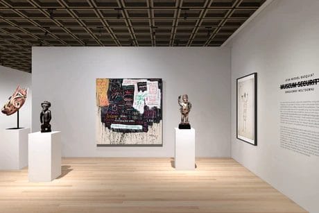 Art gallery interior featuring sculptures and paintings on display with white walls and a wooden floor.