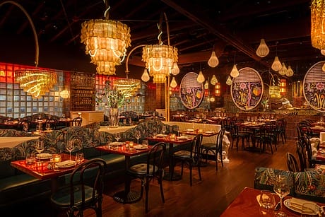 Cozy restaurant interior with warm lighting, elegant chandeliers, and beautifully set tables ready for dining.