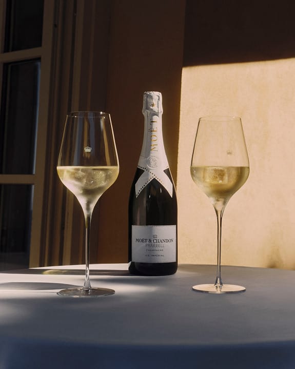 Bottle of Moët & Chandon champagne with two filled glasses on a table.