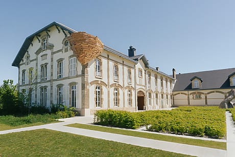 Historic building with a modern wooden structure on the exterior under a clear blue sky.